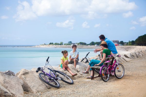 Une famille se balade en velo, le long de la plage de Cleut Rouz